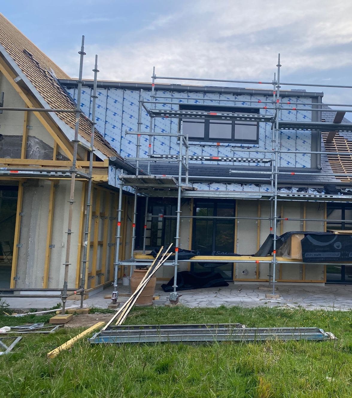 Chantier en cours : ossature bois et écran de façade posés, échafaudage encore en place