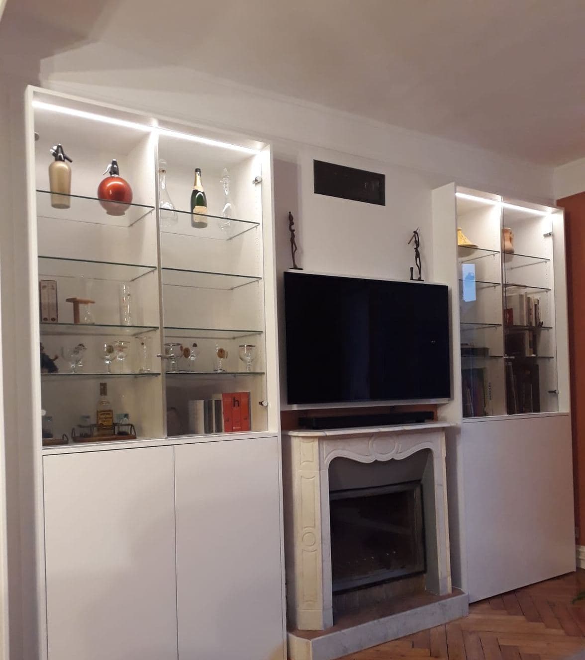 Ensemble menuisé sur mesure de part et d’autre d’une cheminée, avec vitrines éclairées