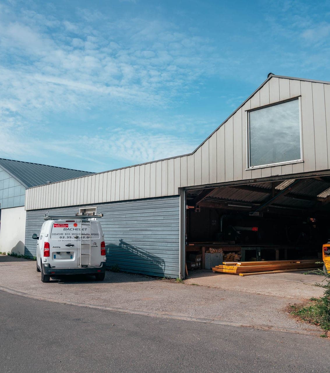 Le hangar de l’entreprise ouvert sur ses bois de charpente, un camion garé devant